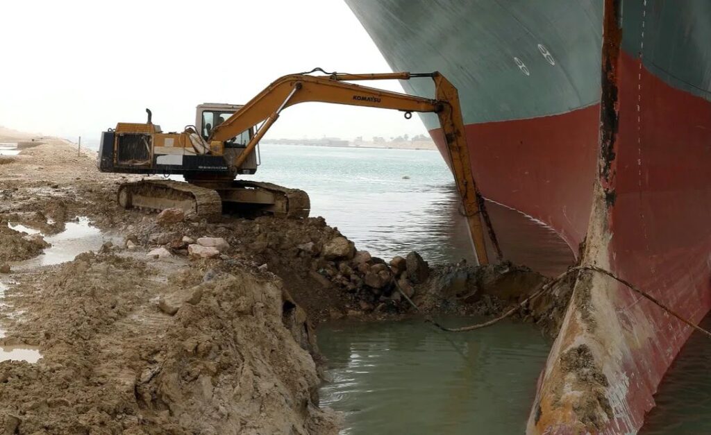 excavator trying to free a container ship stuck across suez canal